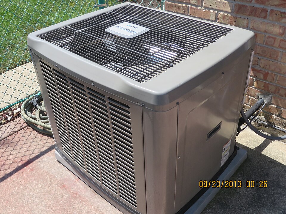 A central air conditioning condenser unit beside a brick house